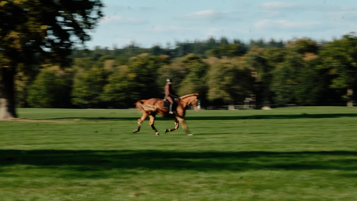 Rider on horseback crossing the polo field at Coworth Park, a Dorchester Collection hotel