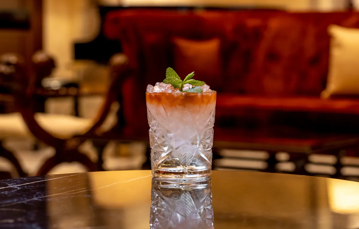 Cocktail in bicchiere da whisky decorato con foglie di menta su di un tavolo a la Libreria, Hotel Eden Roma