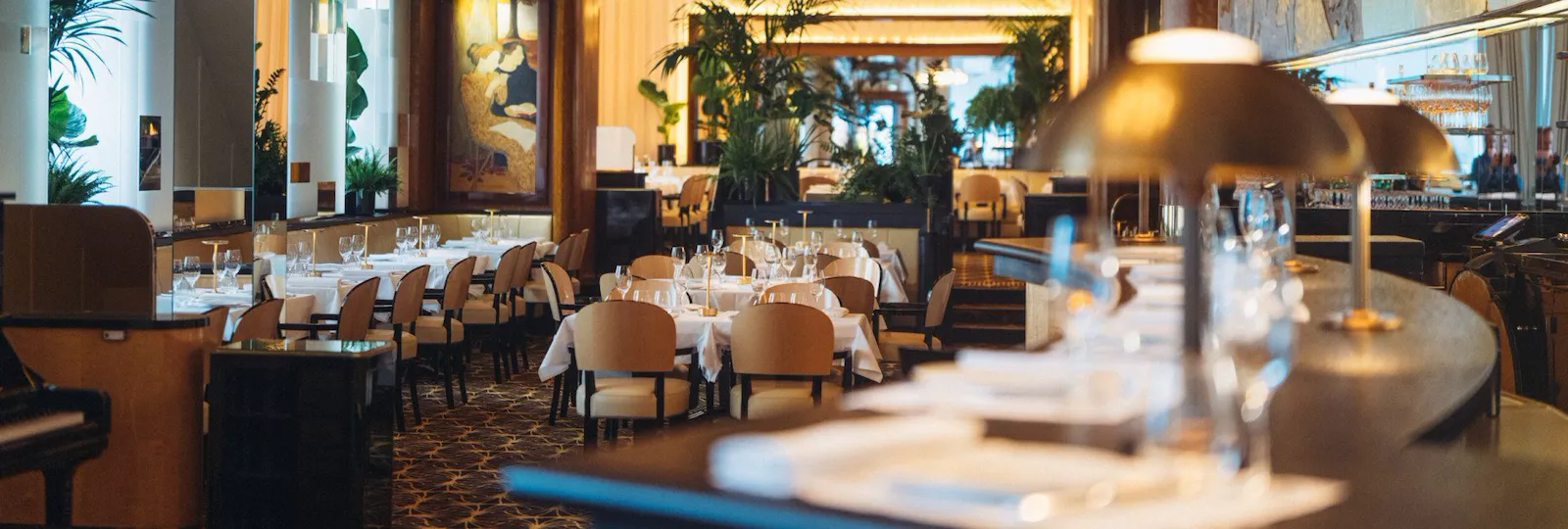 Overview of Le Relais Plaza's dining room lower deck, with the bar at the forefront,at Hotel Plaza Athénée, Paris