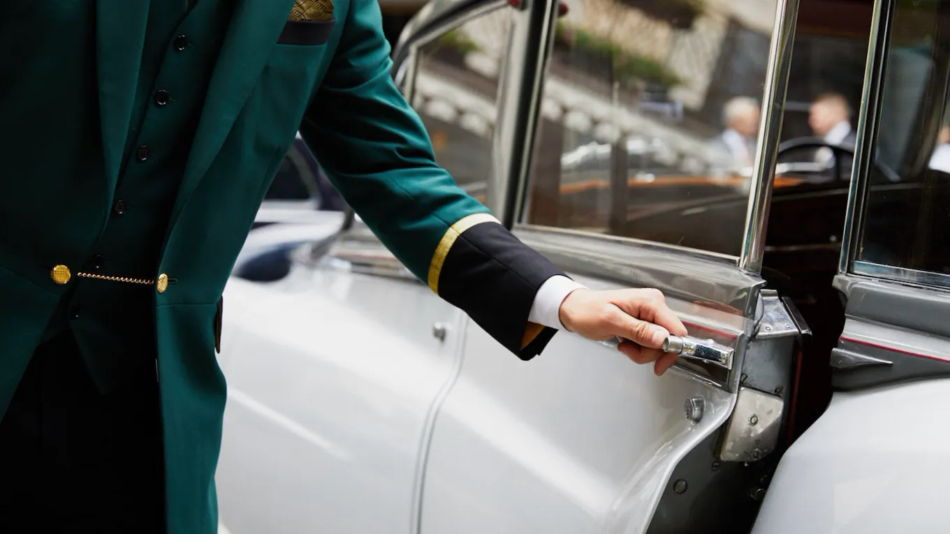 arm of doorman opening vintage car door for guest