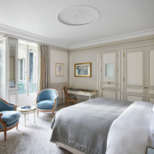 Bedroom of a deluxe suite with blue chairs at Le Meurice, Paris.