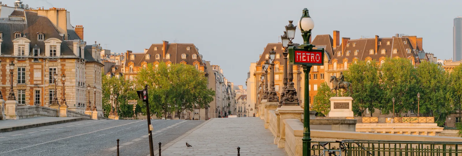 Top view of the bridge, with the road passing on it, with a metro sign and orangey buildings in the back