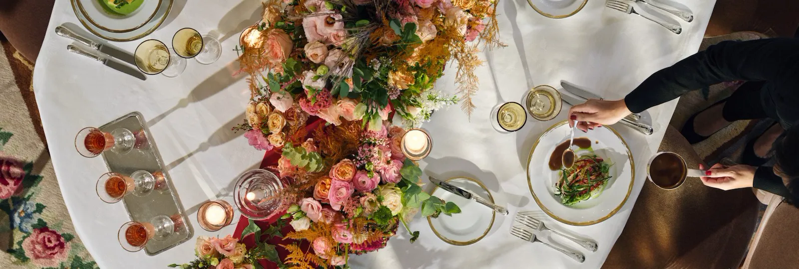 Top view of a person serving dinner, of a table decoratd with flowers in Le Salon Pompadour at Le Meurice, Paris - Dorchester Collection