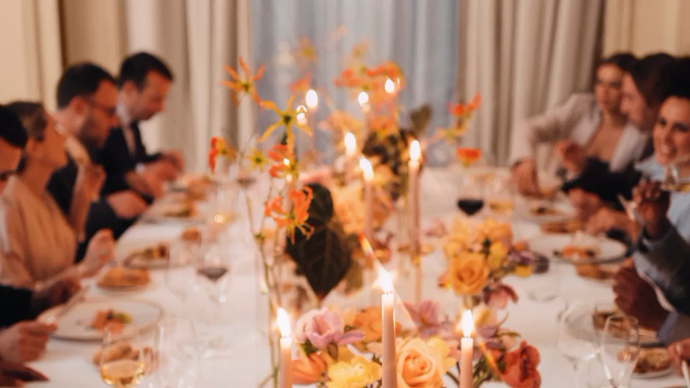 Event dinner with people seated around a table and a large window in the background