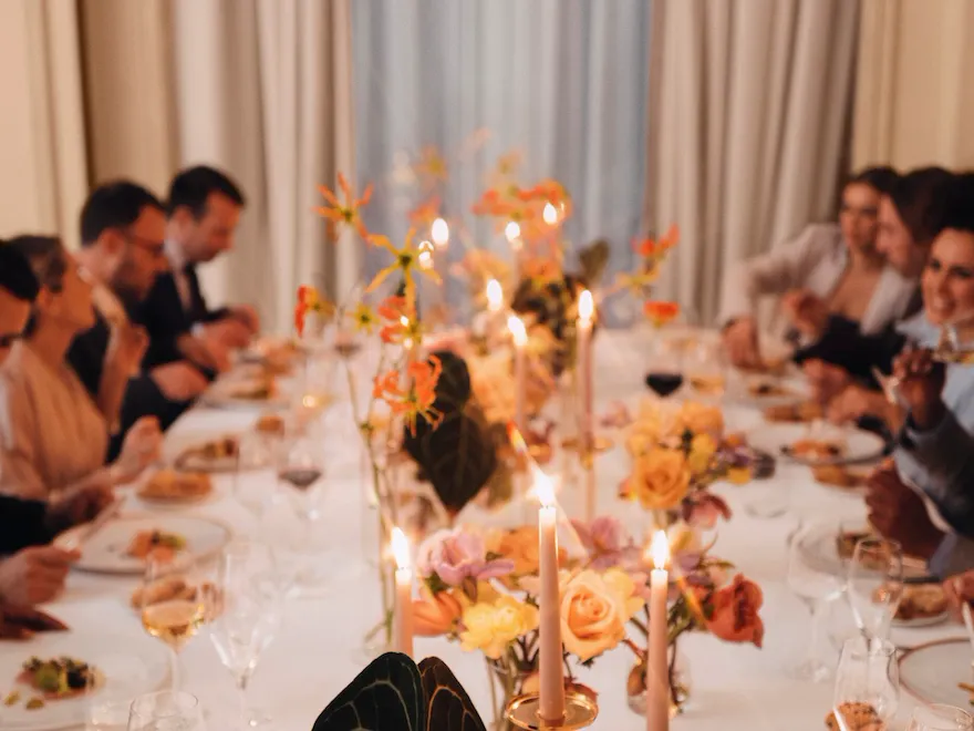 Event dinner with people seated around a table and a large window in the background