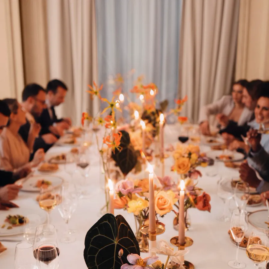 Event dinner with people seated around a table and a large window in the background