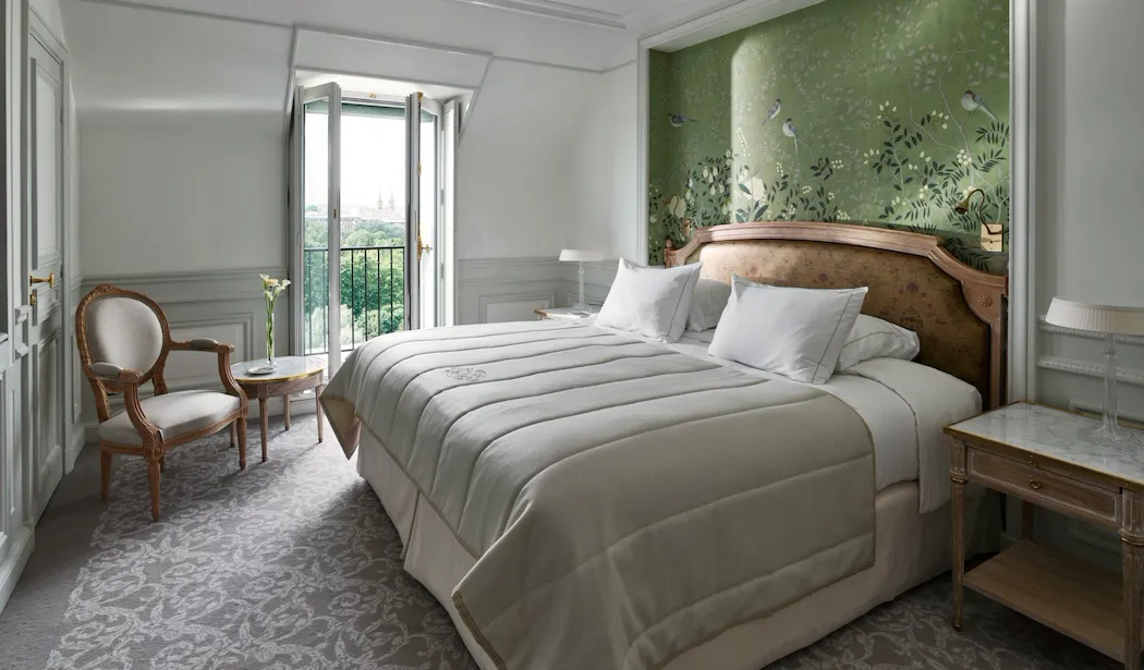 Bedroom side of the superior room, with a green hand painted wall and the view on the Tuileries Garden in the distance. At Le Meurice, Paris.