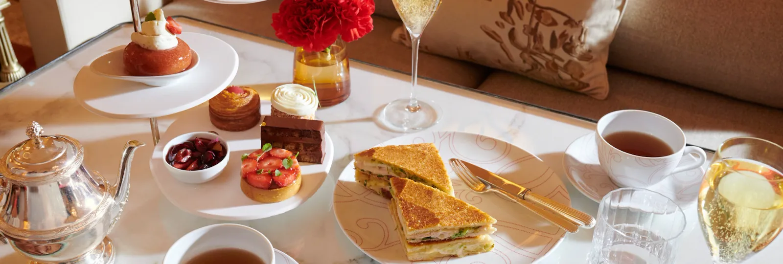 La Galerie Tea Time with a selection of Angelo Musa’s signature pastries, a traditional club sandwich, tea and champaign, set on a marble table, at Hotel Plaza Athénée, Paris