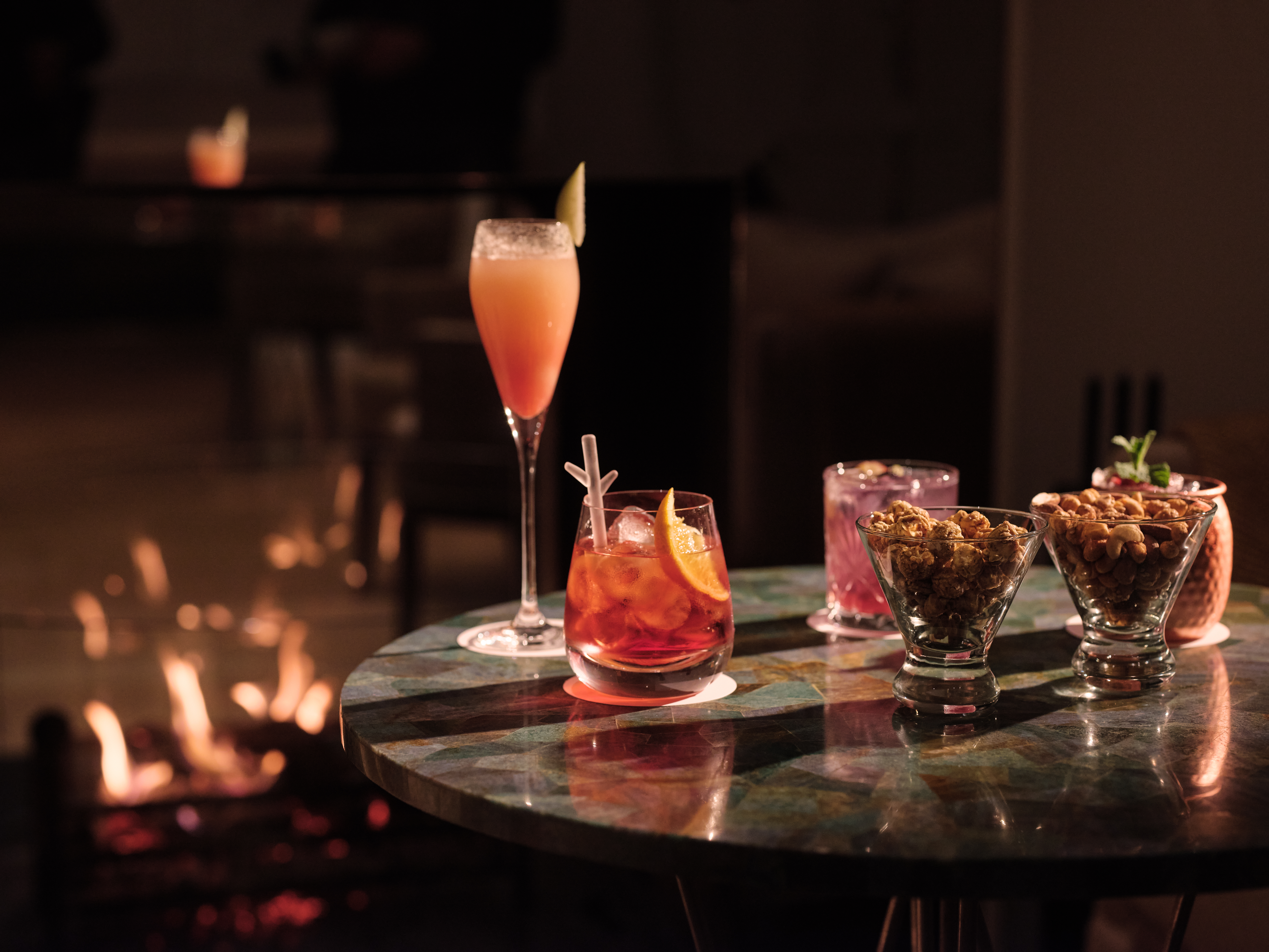 The Bar at Coworth Park cocktails placed on table in front of log fire