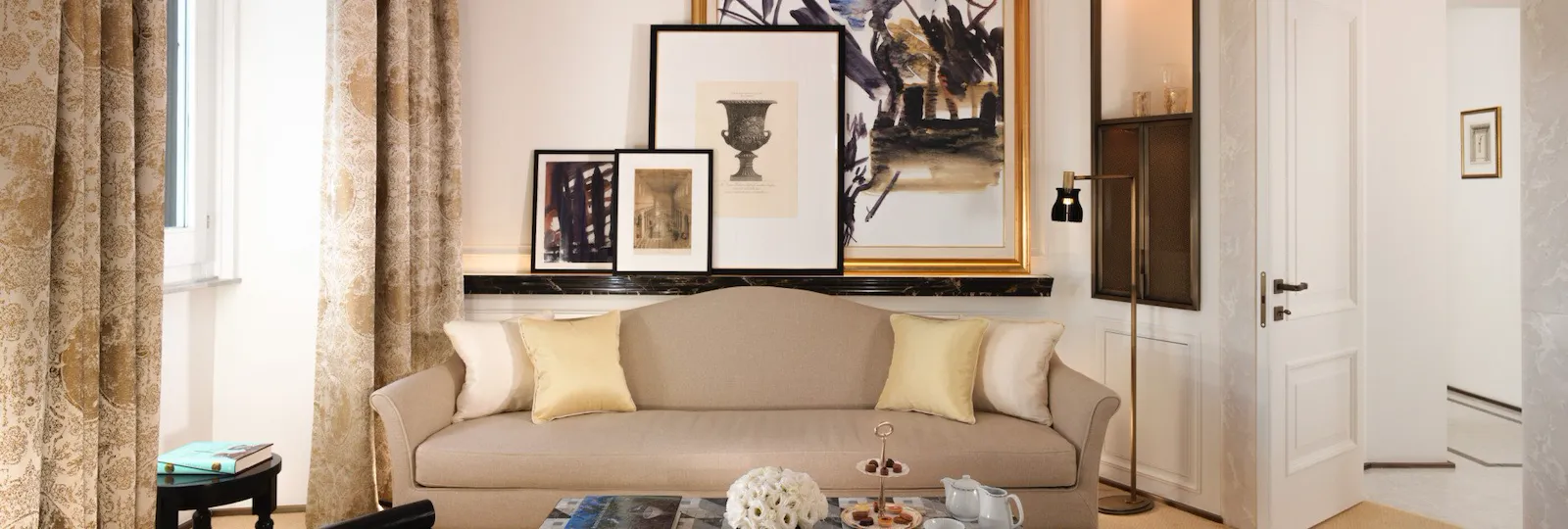 Classic suite living room with beige couch, living table and paintings on the wall