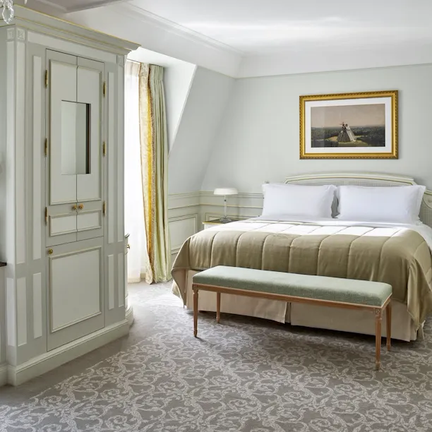 Vista lateral do quarto de uma suíte júnior luxuosa, com tons de verde claro no Le Meurice, Paris