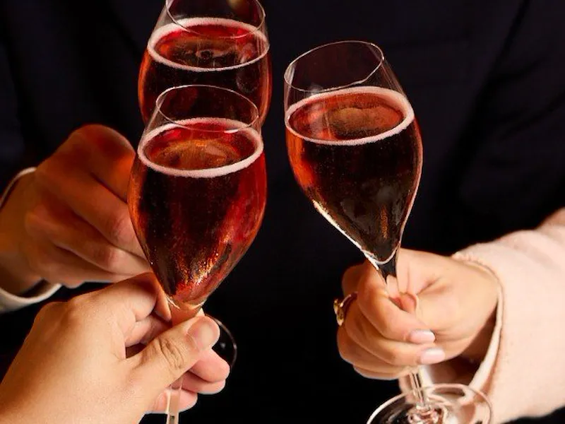 People clinking glasses of sparkling wine in a celebration setting with a marble surface.