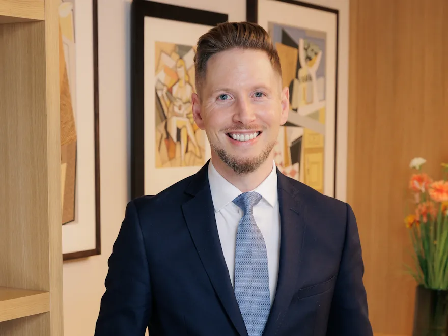 Portrait of Chris Fairless with picture frames hanging in background