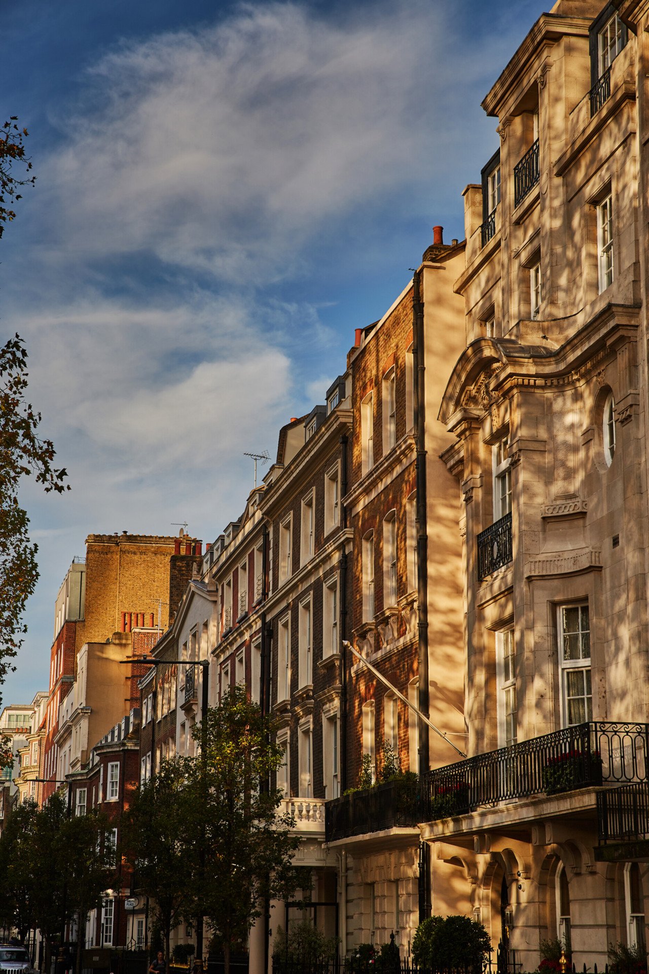 Terraced houses with dappled sunlight on Upper Brooks Street, Mayfair, London