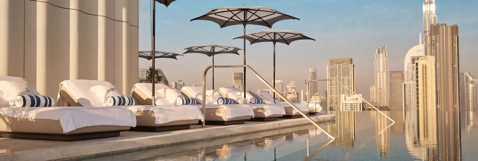 The Lana rooftop pool with sunlongers and view of Downtown Dubai