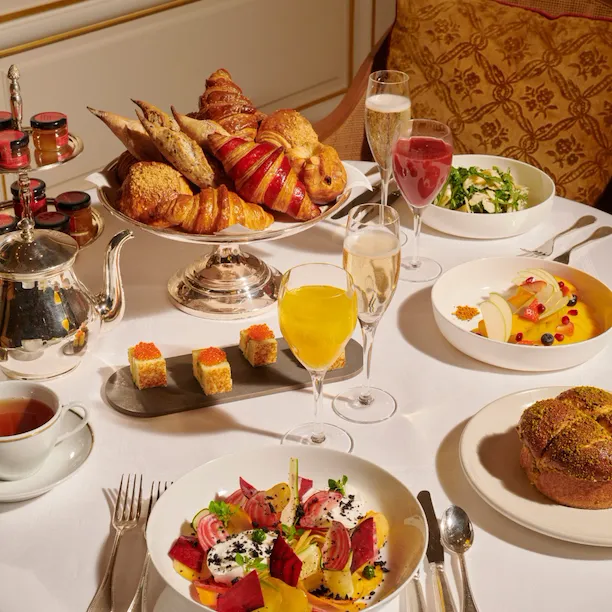 Images du brunch au Jean Imbert au Plaza Athénée. On y voit des pâtisseries, des salades, des fruits, du jus d'orange et du champagne.