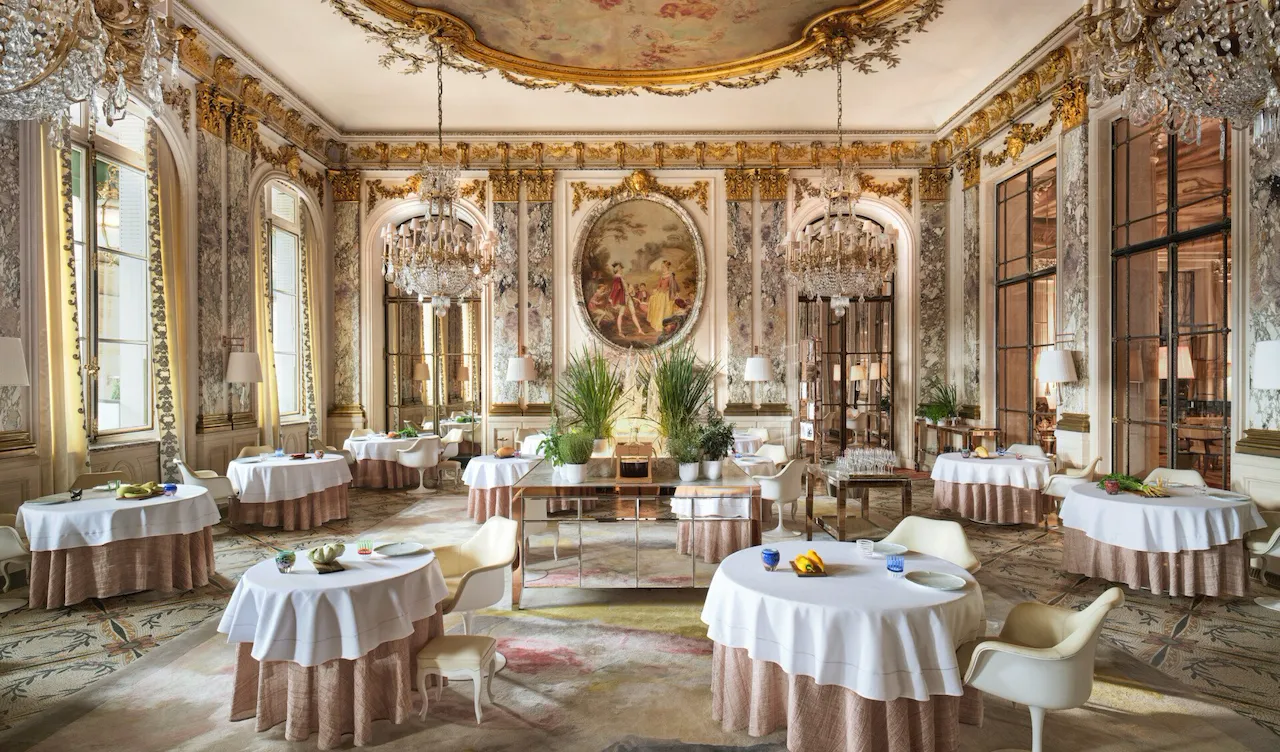 Large view of Le Restaurant le Meurice Alain Ducasse with the furnitures, the chandeliers, the plants and the food on the tables, at Le Meurice, Paris