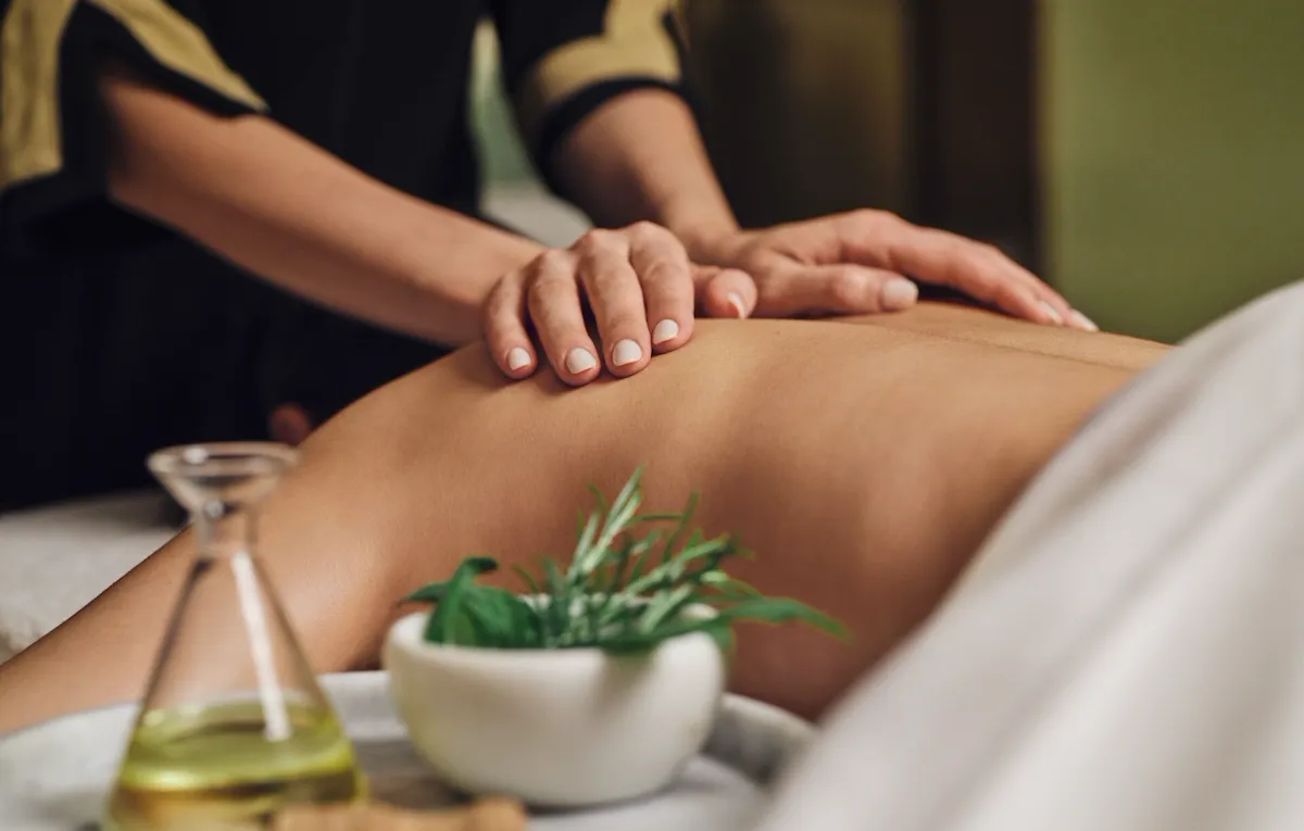 Terapista che massaggia la schiena di una donna distesa a The Eden Spa