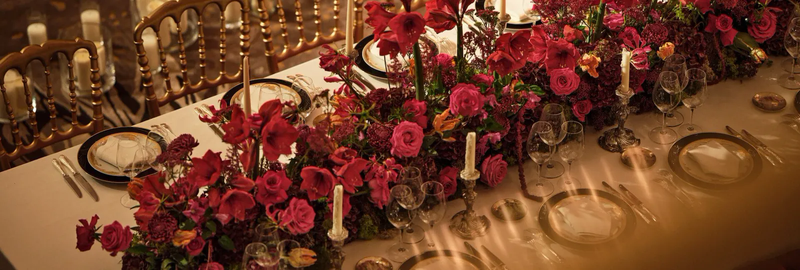 Dinner set up with a long table and red flowers captured from the top in Le Salon Haute Couture, at Hôtel Plaza Athénée, Paris - Dorchester Collection.