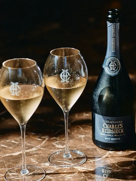 A close up to a Charles Heidsieck Brut Reserve bottle with two full glasses