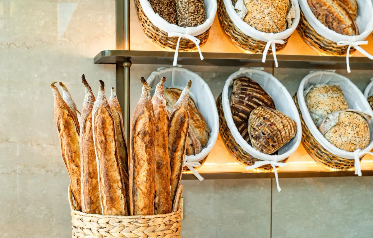 Landscape images of the variety of food and beverage offerings offered at Bonbon Café Angelo Musa, The Lana, Dubai, including chocolates, jams, pastries and bread.