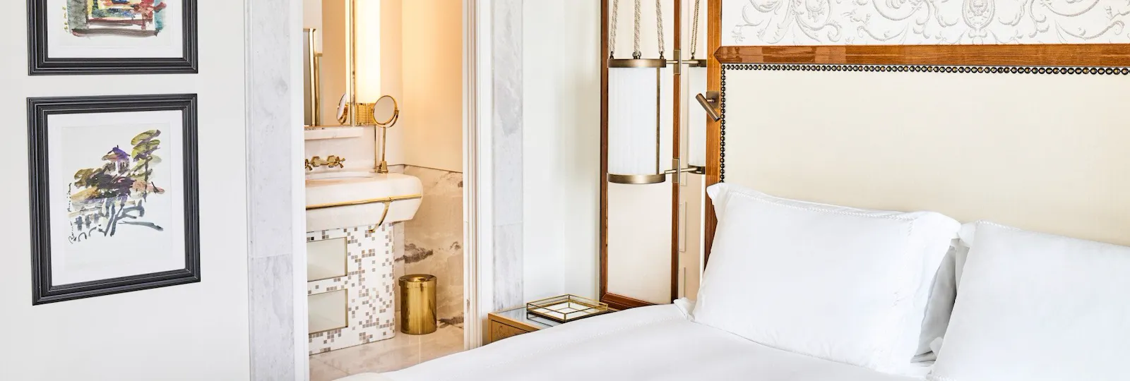 Bedroom of Classic suite with view with paintings on the wall and bathroom in the background at Hotel Eden, Rome