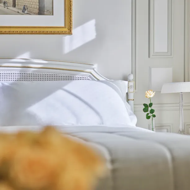 Chambre exécutive près d’un côté du lit avec une rose jaune sur la table d’appoint du lit. Au Meurice, Paris.