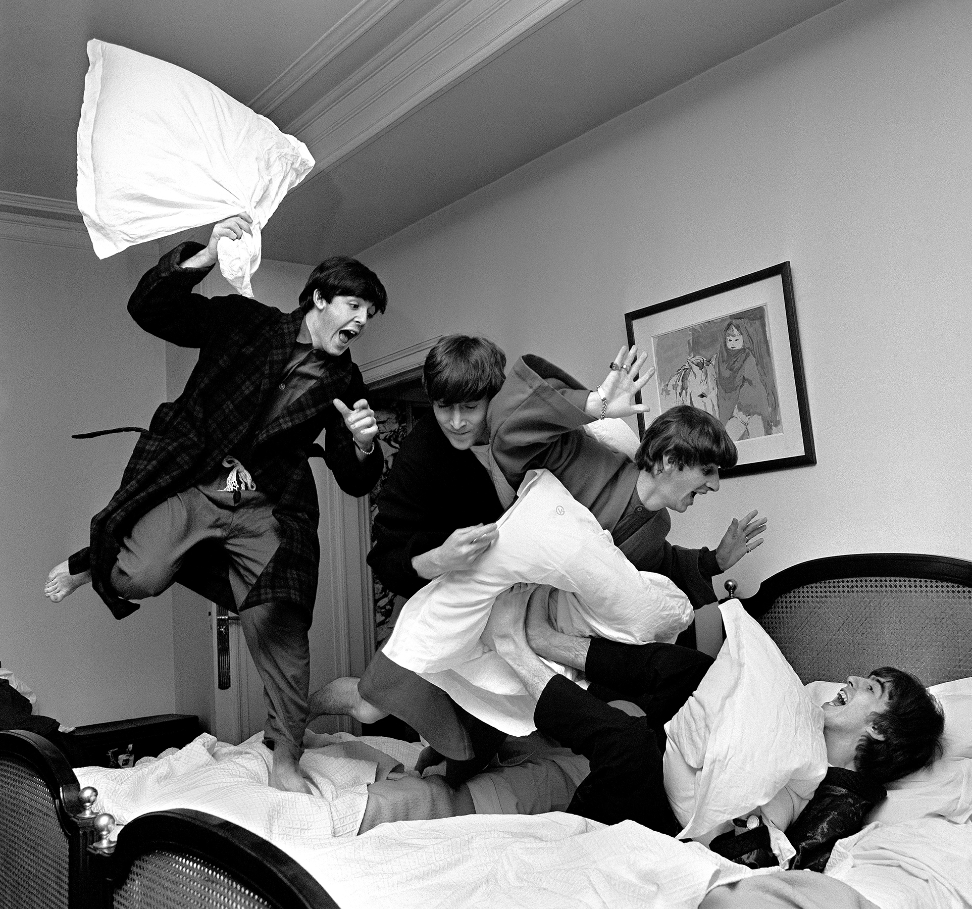 Photograph by Harry Benson of The Beatles jumping on bed at The Beverly Hills Hotel