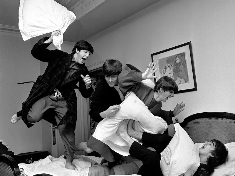 Photograph by Harry Benson of The Beatles jumping on bed at The Beverly Hills Hotel