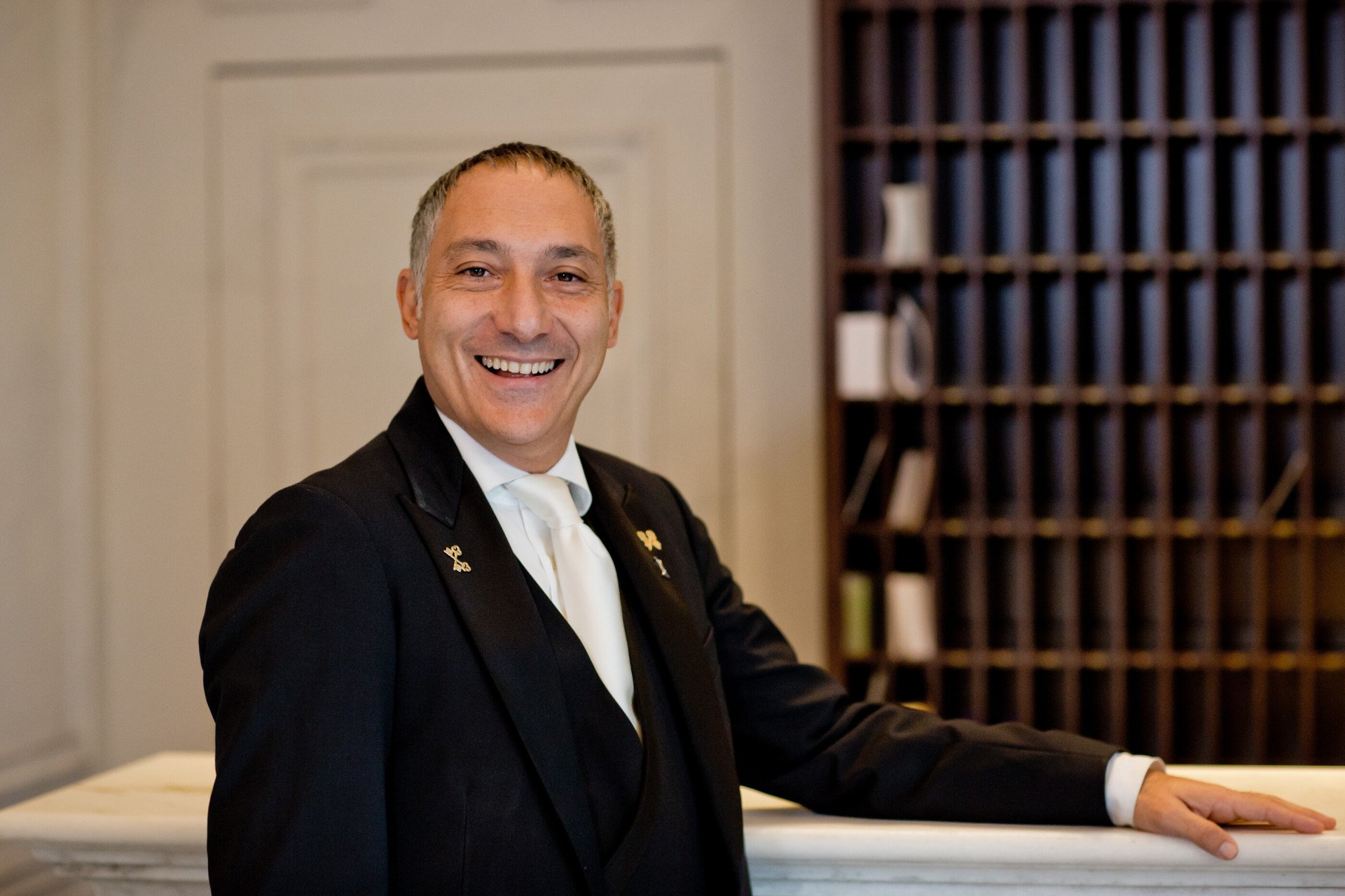 Portrait of Alessandro Arciola Head of Concierge smiling at Concierge desk at Hotel Eden, Rome