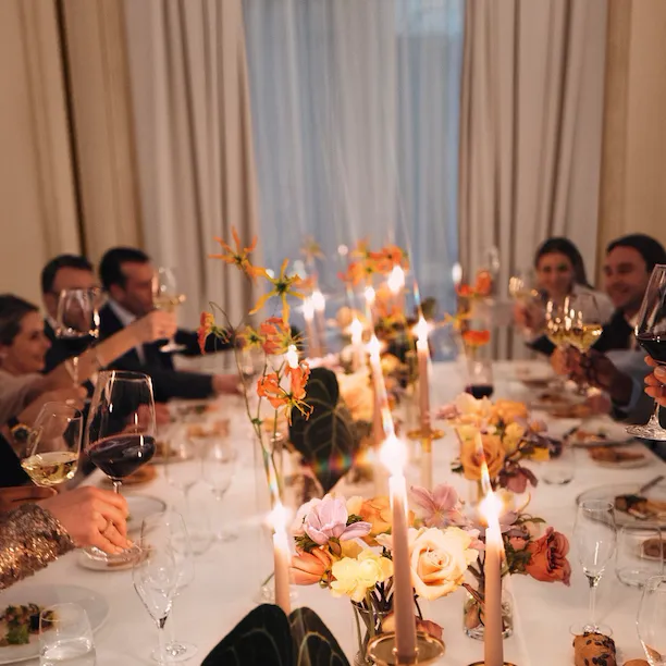 Event dinner with people seated around a table and a large window in the background