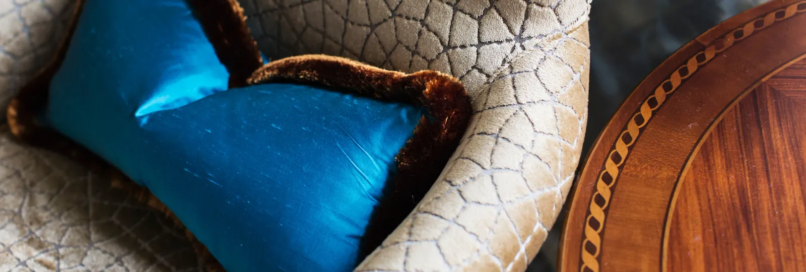 Detail of an armchair with blue pillow and wood coffee table