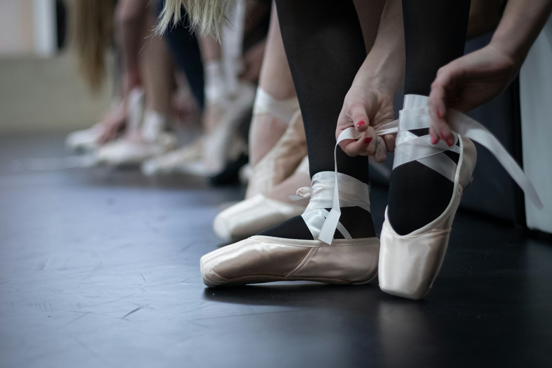 Dancers lacing up ballet shoes photographed by Astrid Schaffner