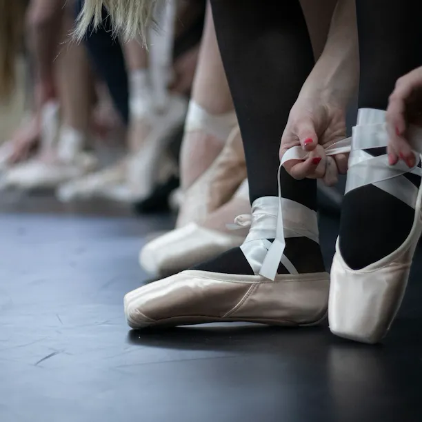 Dancers lacing up ballet shoes photographed by Astrid Schaffner