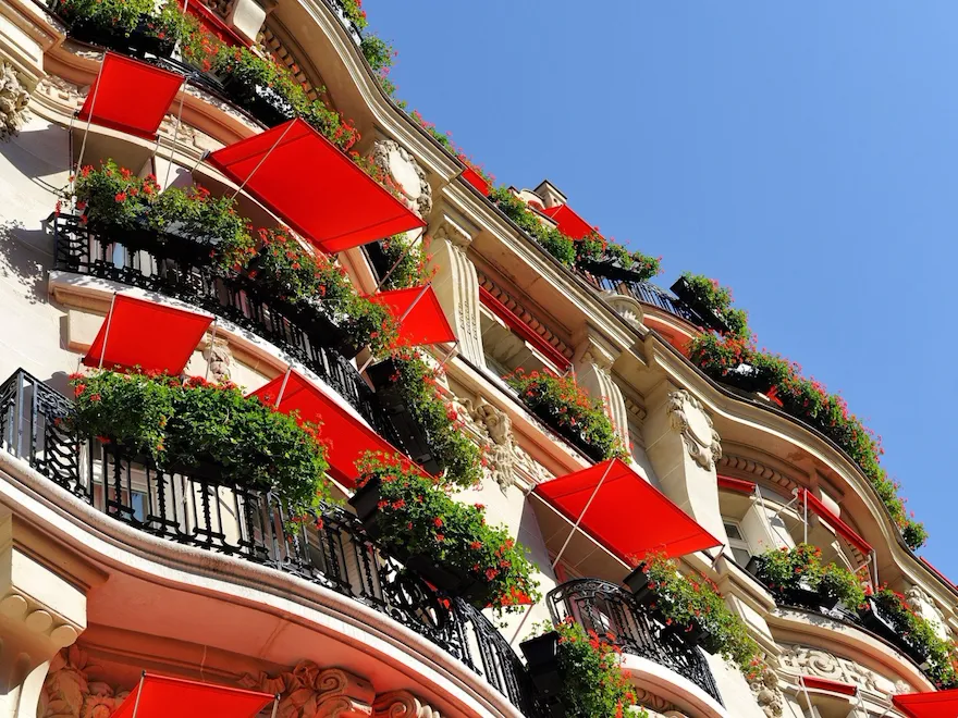 Hôtel Plaza Athénée building facade looking up from street at red awnings over windows, Paris