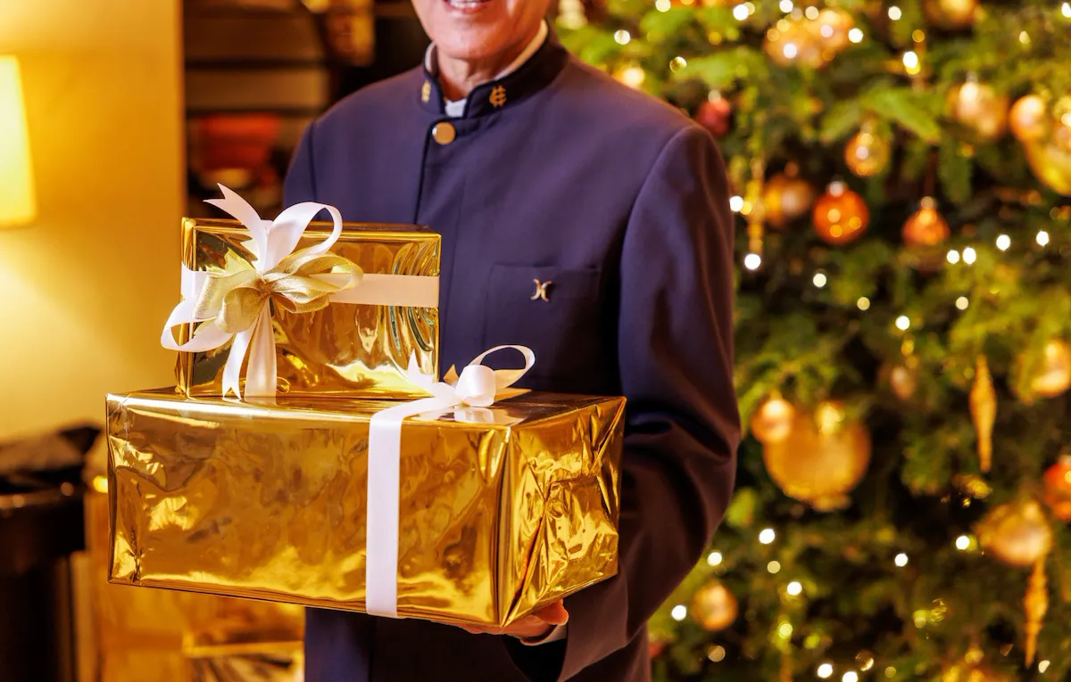 Staff in uniforme che porta due pacchi di Natale nella lobby di Hotel Eden