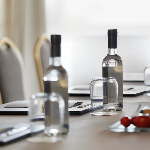 dettaglio di un tavolo di una sala riunioni con acqua, frutta e notes