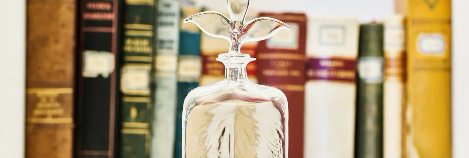 Bottiglia in vetro di Murano davanti a selezione di libri d'antiquariato in una suite di Hotel Eden Roma