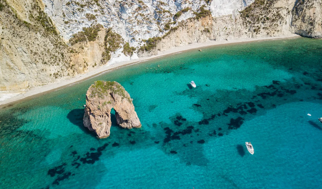 Two boats appear suspended on clear water along the coast of Ponza in Italy