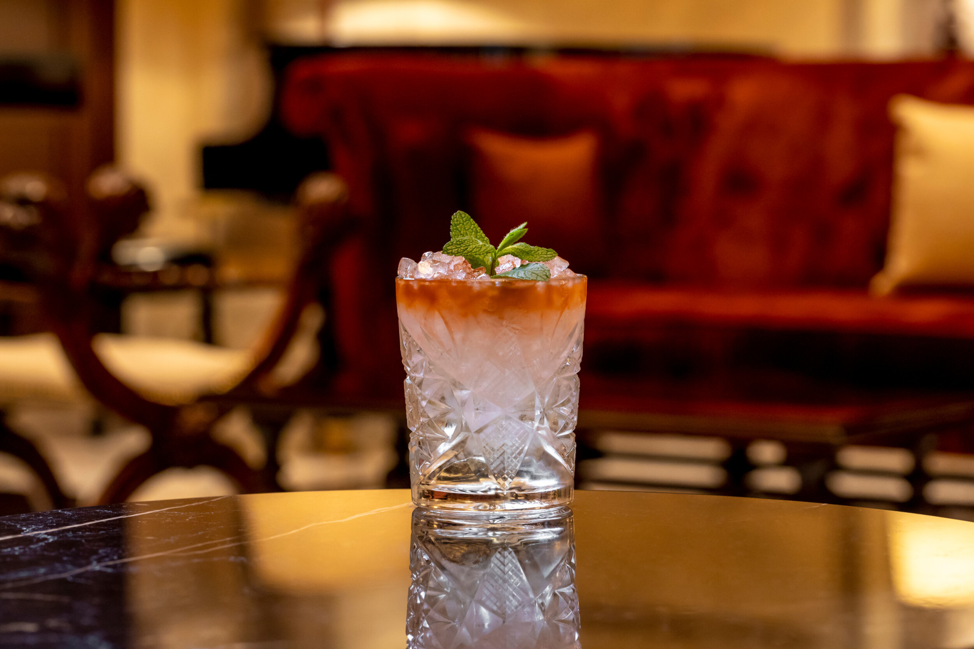 Cocktail with orange hue and mint decoration at La Libreria at Hotel Eden, Rome