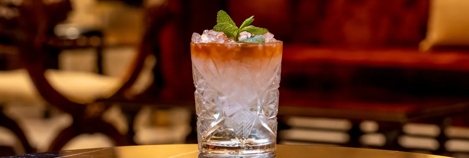 Cocktail in bicchiere da whisky decorato con foglie di menta su di un tavolo a la Libreria, Hotel Eden Roma