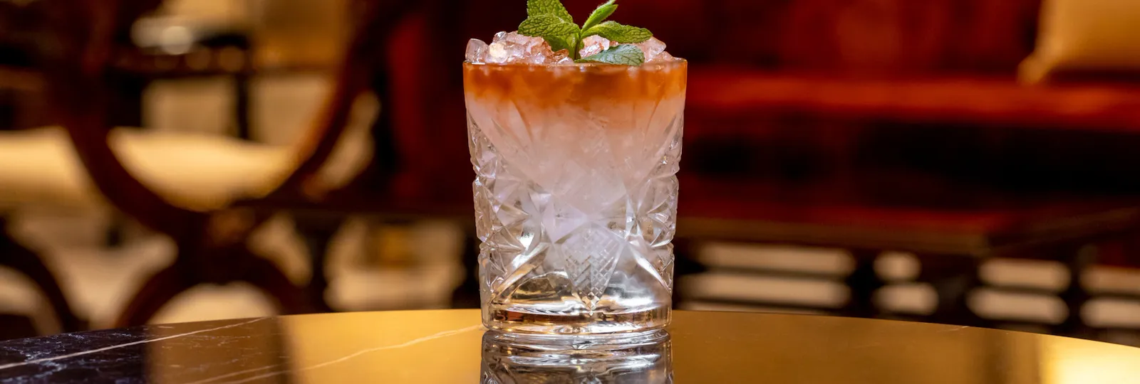 Cocktail with orange hue and mint decoration at La Libreria at Hotel Eden, Rome