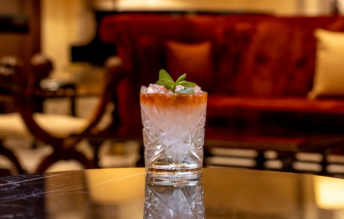 Cocktail with orange hue and mint decoration at La Libreria at Hotel Eden, Rome