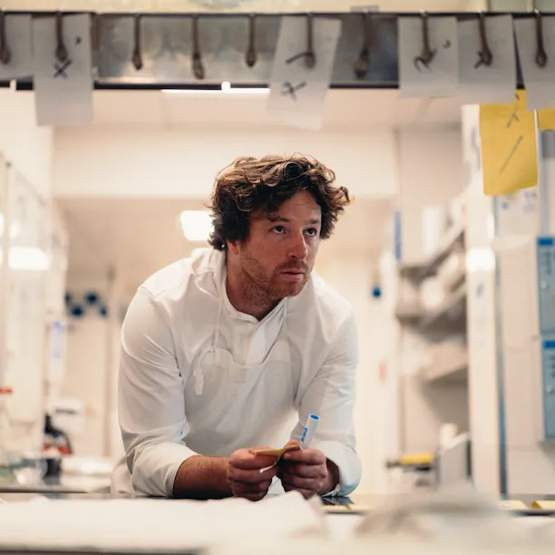 Backstage picture of Chef Jean Imbert leaning on the kitchen counter at Hotel Plaza Athénée, Paris