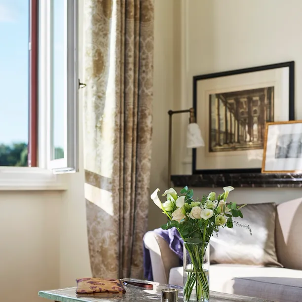 Detail of coffee table with bouquet of flowers and couch of Classic suite with view at Hotel Eden, Rome