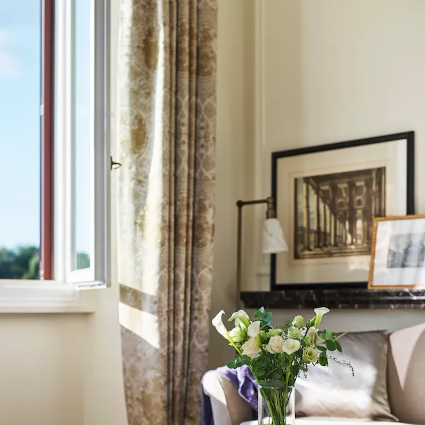 Detail of coffee table with bouquet of flowers and couch of Classic suite with view at Hotel Eden, Rome