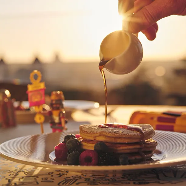 Kids breakfast made of pankakes, with syrup poured on top.