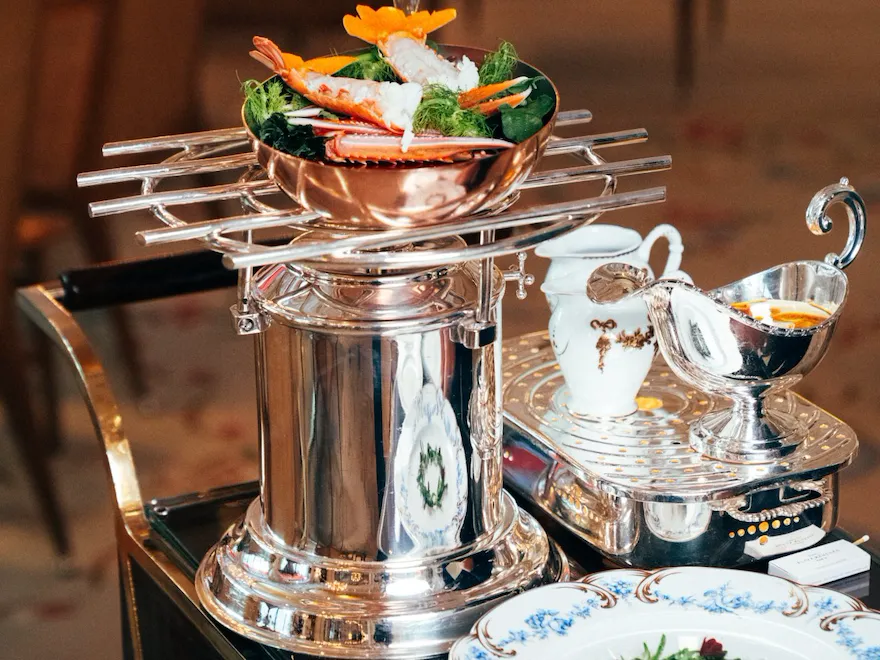 Acht-person setting with decorative food and ornate tableware on a polished surface.