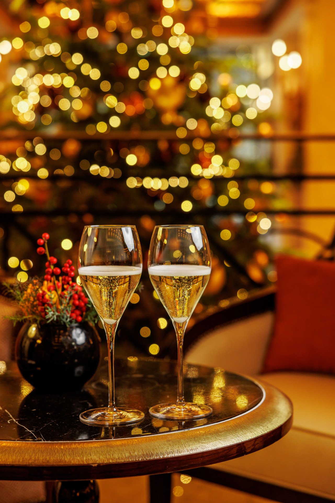 Due calici di champagne appoggiati su un tavolo con un albero di natale sullo sfondo