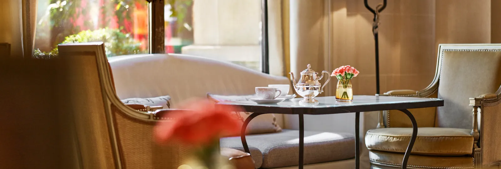 Close up of a dining table at la galerie, table with cups of tea, two armchairs and a sofa next to a sunny window, at Hotel Plaza Athénée, Paris